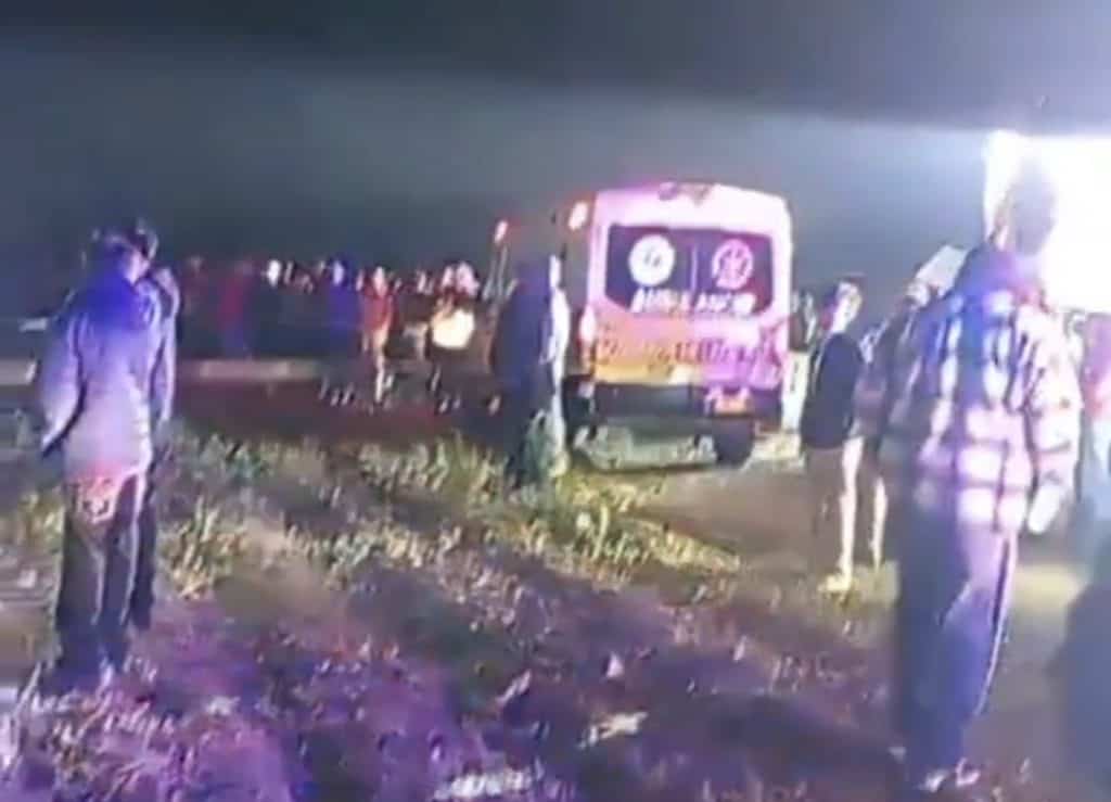 Accidente carretera en noche con ambulancia y personas en escena, atención médica en acción.