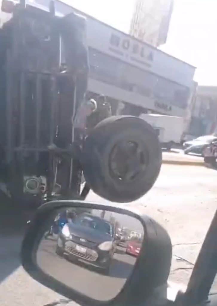 Auto volcada en la calle, accidente vial en la ciudad, imagen de un vehículo volteado, vista desde el espejo lateral.