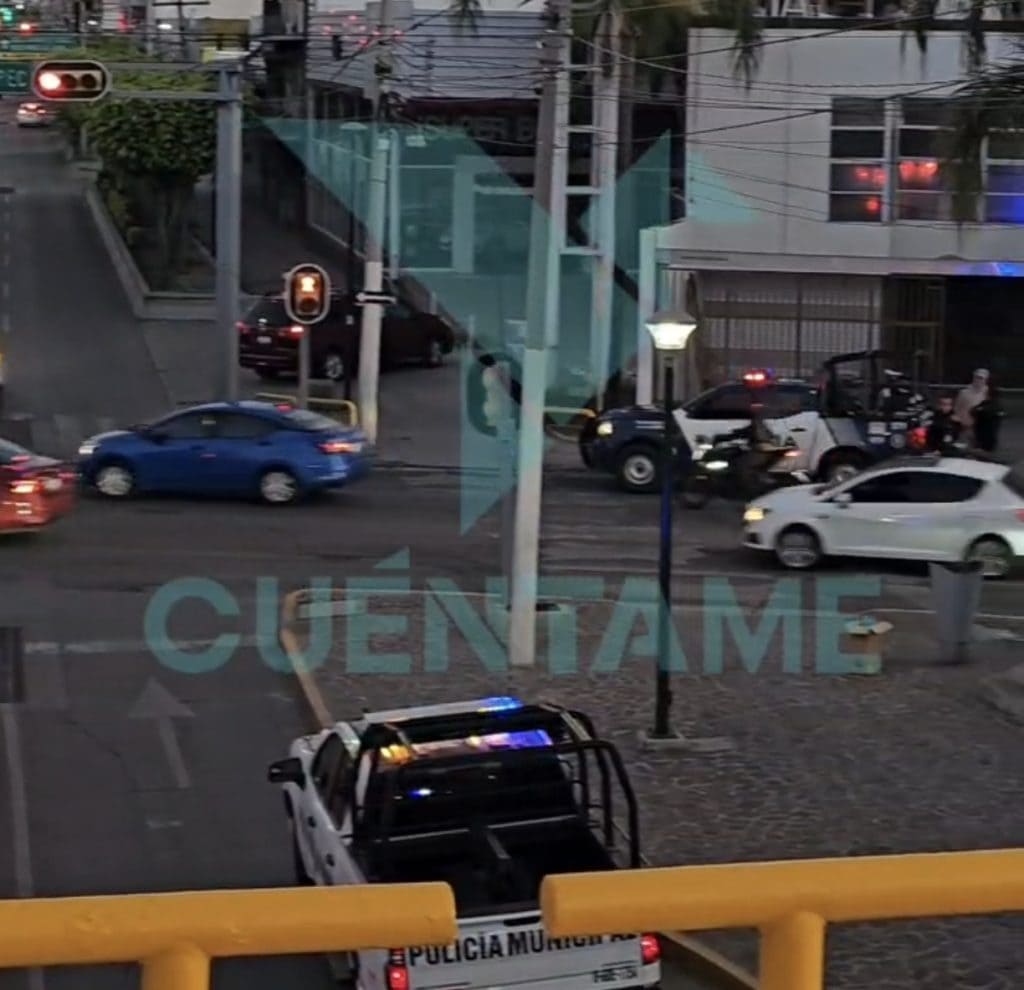 Autos en cruce con semáforo en rojo en ciudad mexicana, vista desde interior de un edificio.