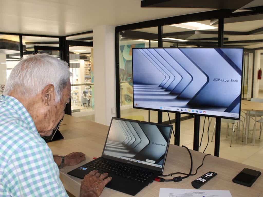 Tecnología moderna para adultos mayores, uso de computadora en centro comunitario.