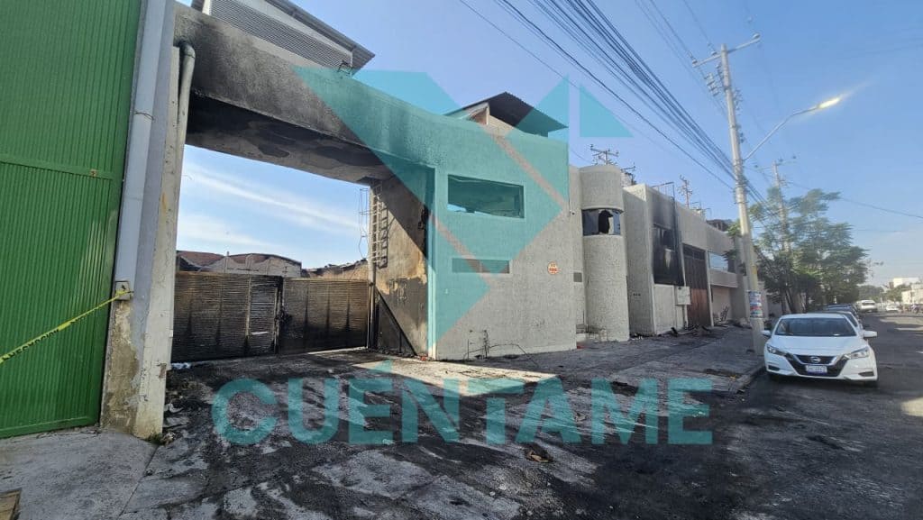 Puerta de garaje quemada, edificio dañado y calles en desastre en la zona urbana de Cuentame.