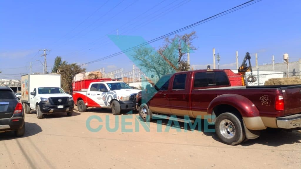 Coches y vehículos de emergencia en un área de construcción o reparación en la calle, bajo un cielo azul despejado.