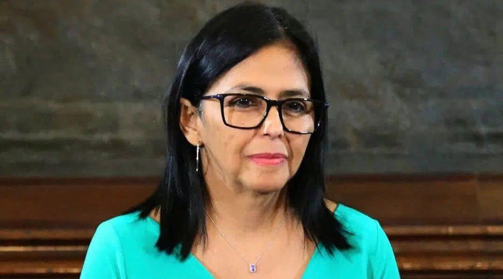 Delcy Rodríguez asume como presidenta encargada de Venezuela; recibe respaldo de hijo de Maduro Maestra de edad madura con gafas negras y cabello negro, usando blusa azul, en ambiente formal.