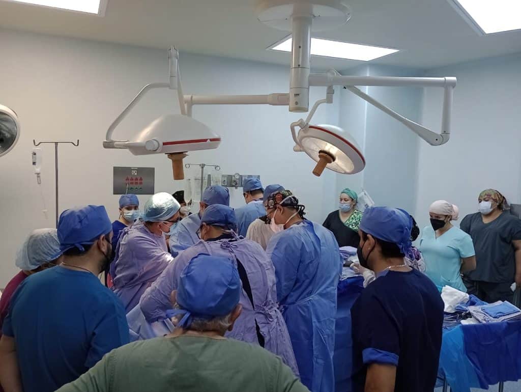 Equipo médico realizando cirugía en quirófano con tecnología avanzada.