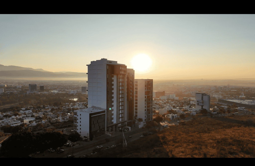 El horizonte urbano de la ciudad al atardecer con edificios altos y paisaje montañoso en el fondo.