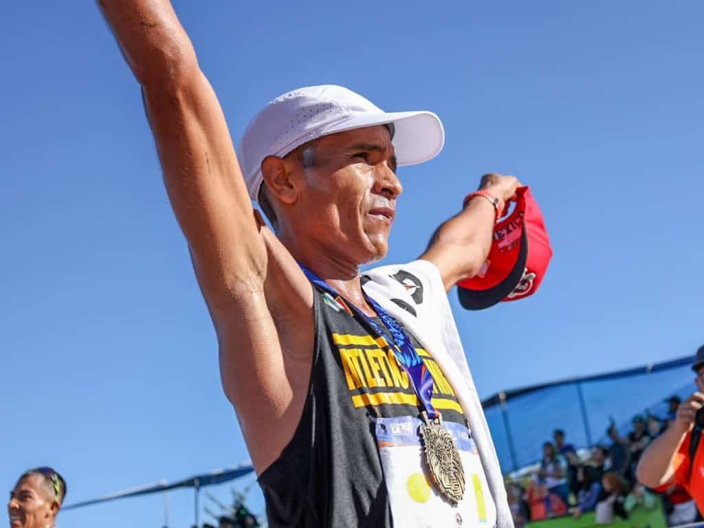 Atleta con medalla en competencia de atletismo en exteriores, celebrando logro.