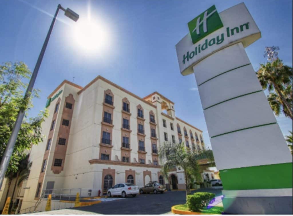 Fin de semana de puente deja ocupación hotelera casi al 100% en León Hotel Holiday Inn frente a edificio colonial en clima soleado con palmeras.