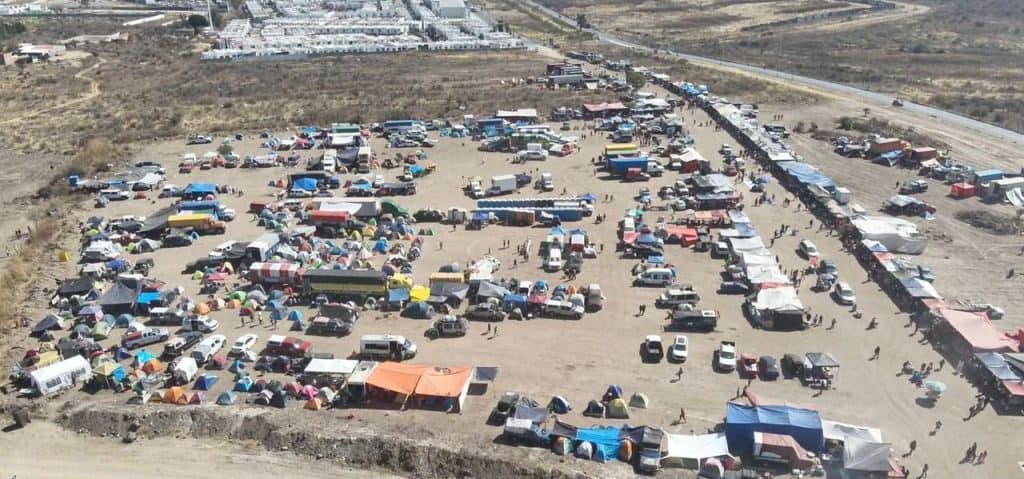 La imagen muestra un mercado al aire libre con numerosos puestos y vehículos en un entorno árido.